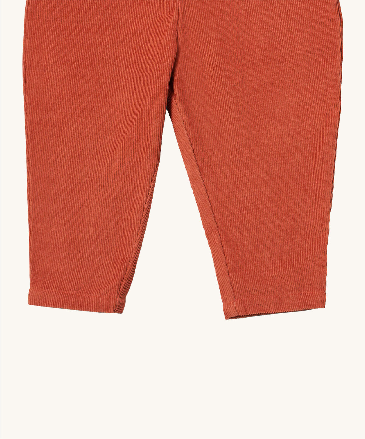 A close up of the Little Green Radicals comfy trousers in ginger corduroy. Showing the corduroy detail on dark orange organic cotton fabric