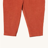 A close up of the Little Green Radicals comfy trousers in ginger corduroy. Showing the corduroy detail on dark orange organic cotton fabric