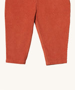 A close up of the Little Green Radicals comfy trousers in ginger corduroy. Showing the corduroy detail on dark orange organic cotton fabric
