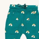 A close up  the Little Green Radicals turquoise rainbow joggers showing the turquoise drawstring, 2 side pockets and stitched on knee patches  on organic cotton fabric.
