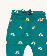 A close up  the Little Green Radicals turquoise rainbow joggers showing the turquoise drawstring, 2 side pockets and stitched on knee patches  on organic cotton fabric.