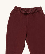 A close up of the Little Green Radicals comfy trousers in chocolate corduroy. Showing the corduroy detail and matching drawstring in dark maroon soft GOTS organic cotton fabric