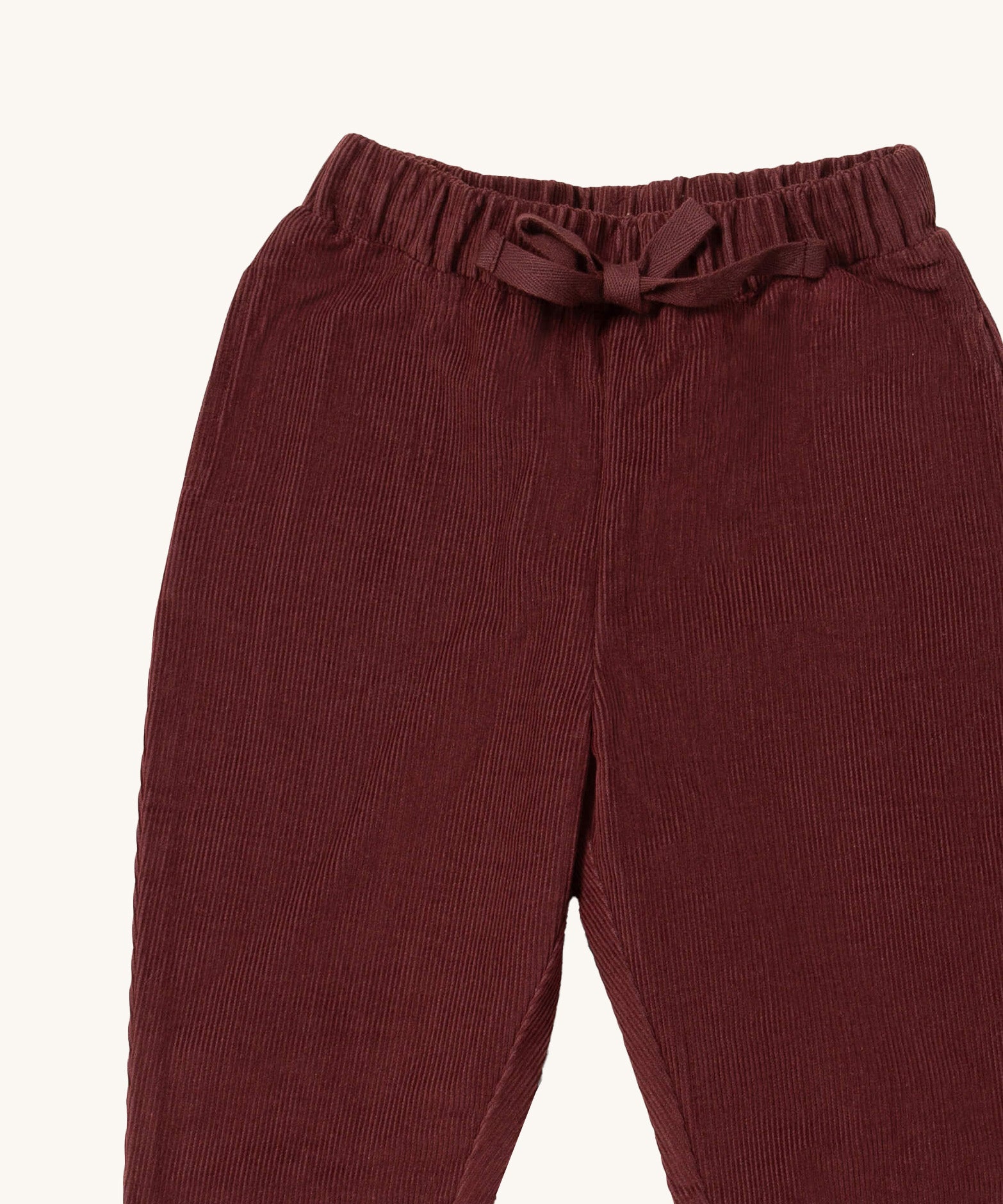 A close up of the Little Green Radicals comfy trousers in chocolate corduroy. Showing the corduroy detail and matching drawstring in dark maroon soft GOTS organic cotton fabric
