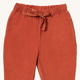 A close up of the Little Green Radicals comfy trousers in ginger corduroy. Showing the corduroy detail and matching drawstring in dark orange soft GOTS organic cotton fabric