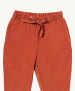 A close up of the Little Green Radicals comfy trousers in ginger corduroy. Showing the corduroy detail and matching drawstring in dark orange soft GOTS organic cotton fabric