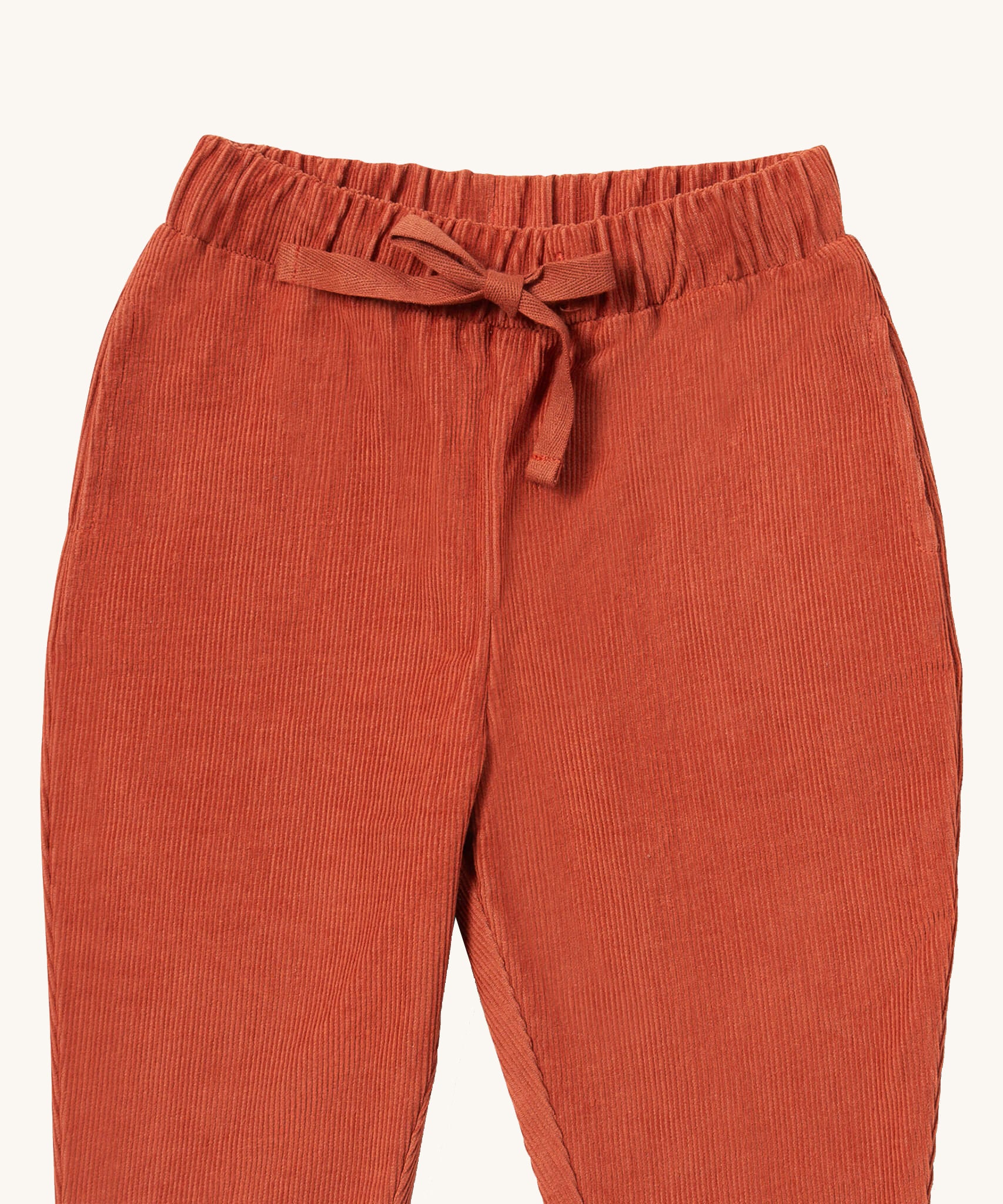 A close up of the Little Green Radicals comfy trousers in ginger corduroy. Showing the corduroy detail and matching drawstring in dark orange soft GOTS organic cotton fabric