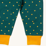 A close up  the Little Green Radicals golden stars cosy joggers showing the stitched on knee patches  and yellow cuff trim on soft organic cotton fabric
