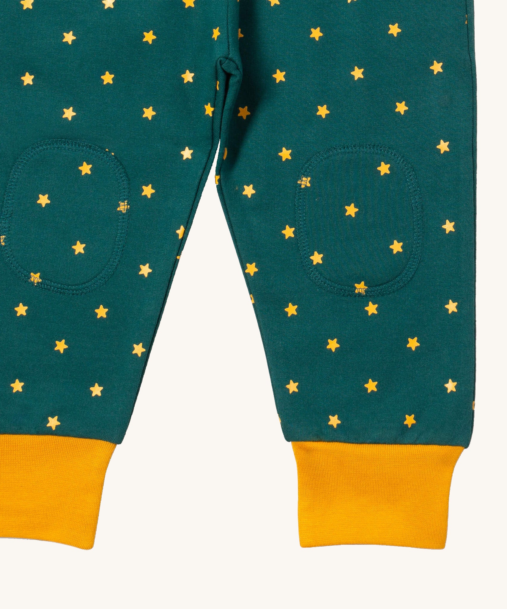 A close up  the Little Green Radicals golden stars cosy joggers showing the stitched on knee patches  and yellow cuff trim on soft organic cotton fabric