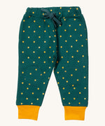Little Green Radicals cosy joggers in golden stars available at Babipur.. A soft GOTS organic cotton dark turquoise jogger pants with yellow stars and matching yellow trim. Features 2 side pockets a matching turquoise waist drawstring and knee patches.