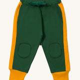 Little Green Radicals cosy joggers in olive available at Babipur.. A soft GOTS organic cotton green jogger pants with a yellow stripe on the side and matching yellow trim. Features 2 side pockets a matching green waist drawstring and knee patches.