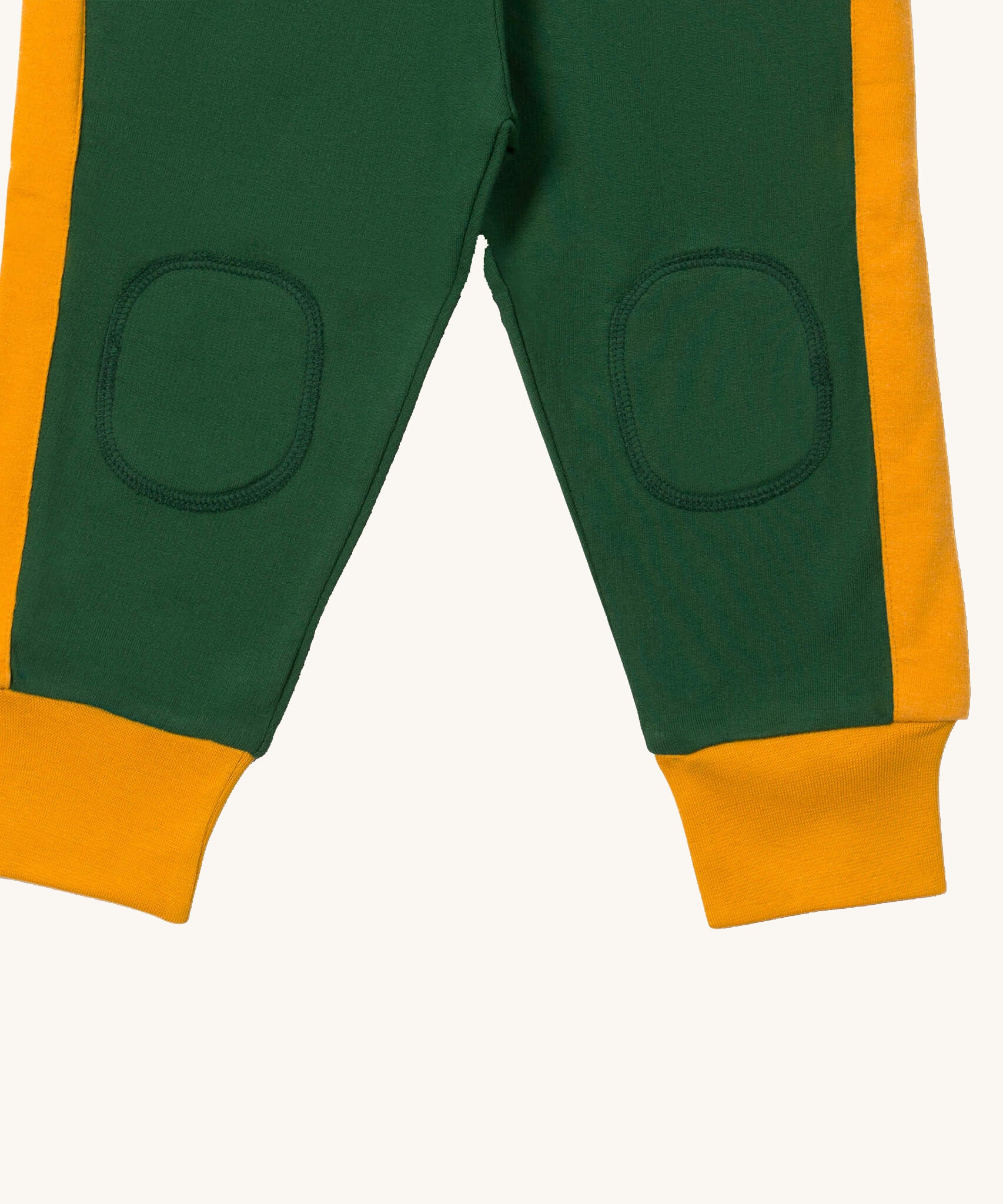 A close up  the Little Green Radicals golden stars cosy joggers showing the stitched on knee patches and yellow cuff trim on soft green organic cotton fabric