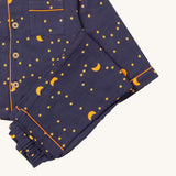 A close up of the Little Green Radicals classic dark night pyjama set showing the organic cotton navy bottoms laid on top of the matching pyjama top.