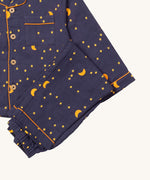 A close up of the Little Green Radicals classic dark night pyjama set showing the organic cotton navy bottoms laid on top of the matching pyjama top.