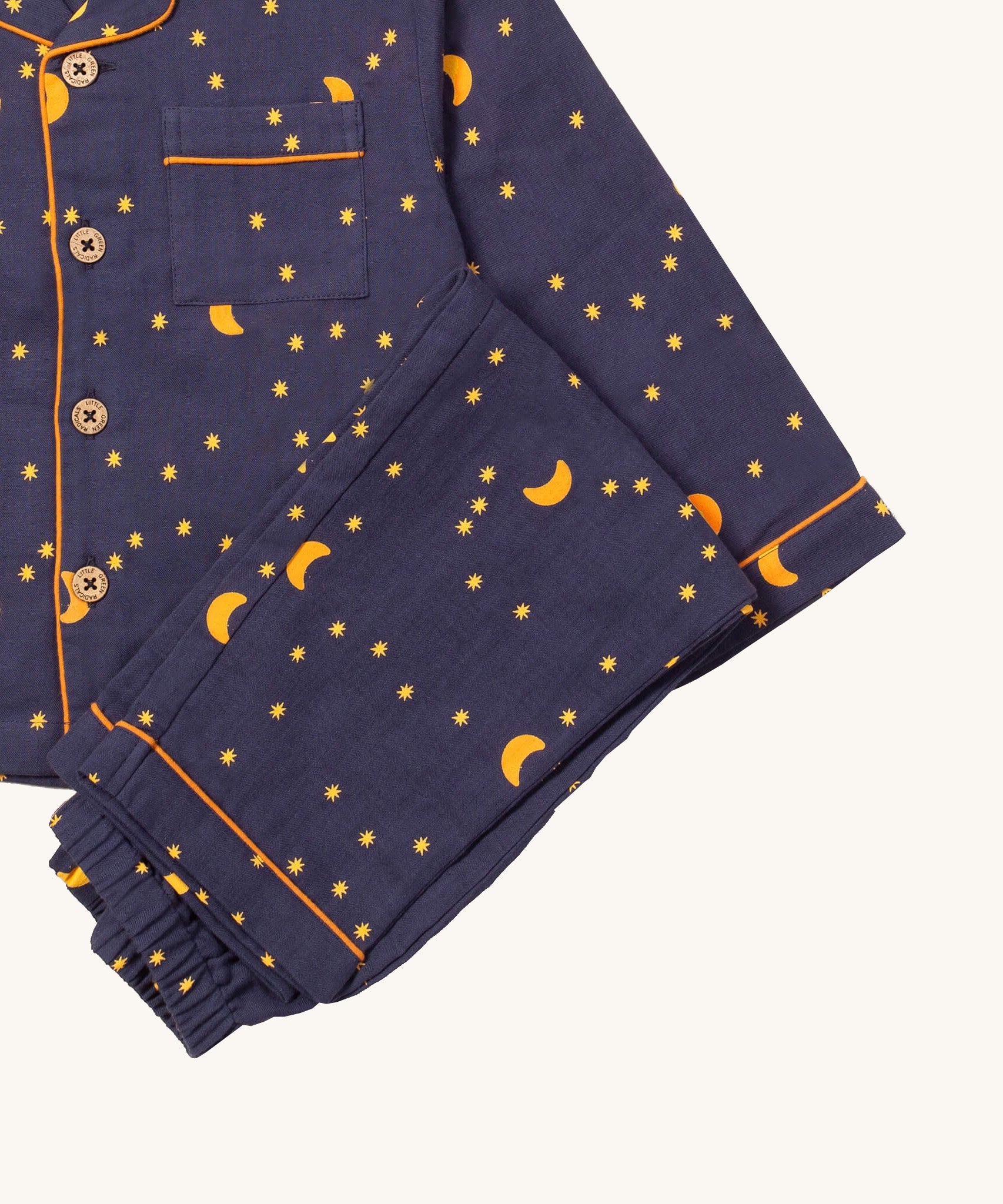 A close up of the Little Green Radicals classic dark night pyjama set showing the organic cotton navy bottoms laid on top of the matching pyjama top.