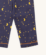 A close up of the Little Green Radicals classic pyjama bottoms from the dark night classic set. Showing the yellow trim around the bottom of the legs and a close up of the starry night print on navy organic cotton fabric.