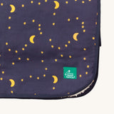 A close up of the Little Green Radicals dark night sherpa hooded blanket. Showing the brand patch detail stitched on the corner on navy soft organic cotton fabric