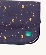 A close up of the Little Green Radicals dark night sherpa hooded blanket. Showing the brand patch detail stitched on the corner on navy soft organic cotton fabric