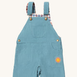 A close up of the Little Green Radicals pale blue lined corduroy dungarees available at Babipur. Showing the 3 pockets and shoulder strap detail on blue organic cotton fabric