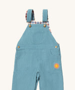 A close up of the Little Green Radicals pale blue lined corduroy dungarees available at Babipur. Showing the 3 pockets and shoulder strap detail on blue organic cotton fabric