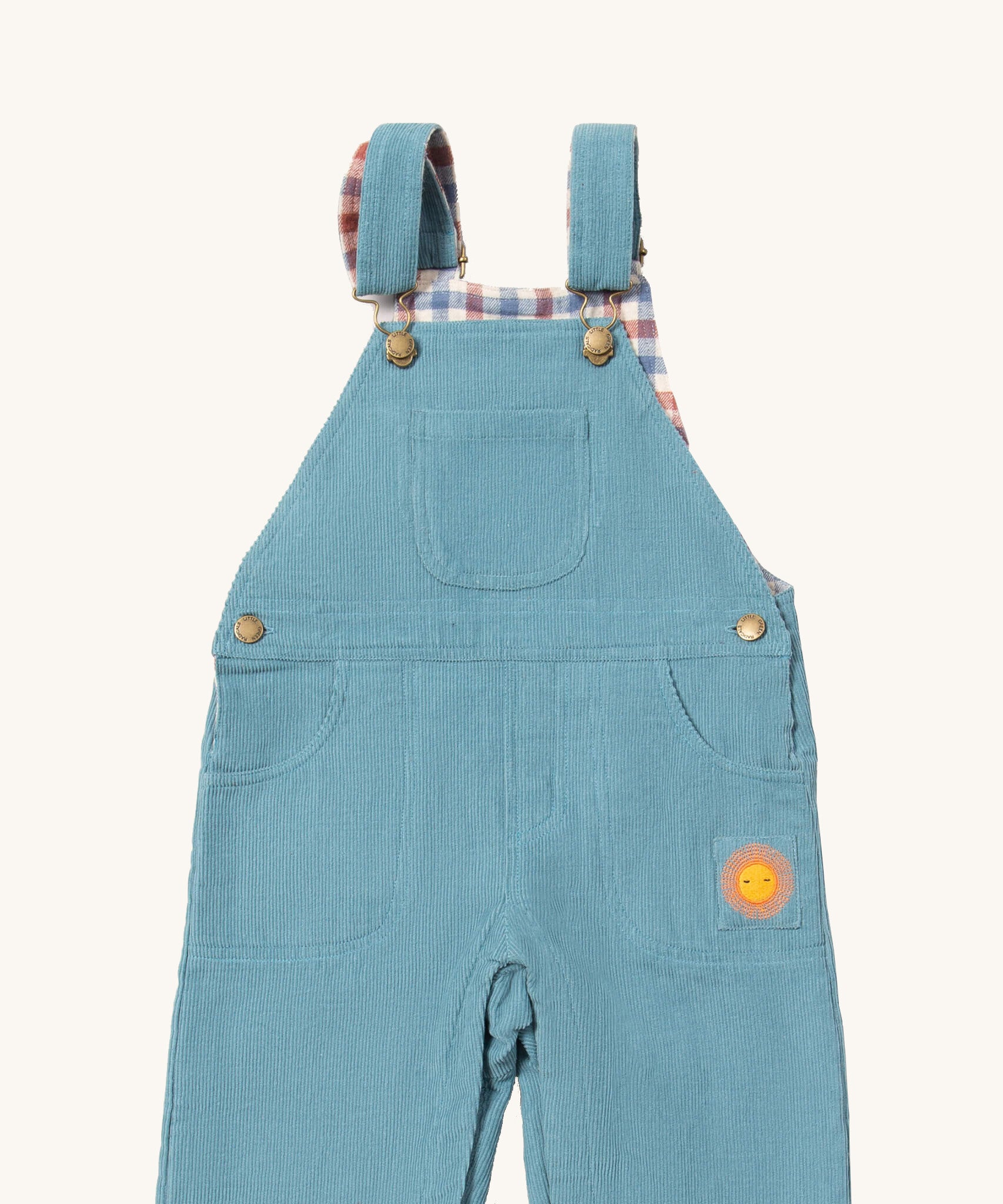 A close up of the Little Green Radicals pale blue lined corduroy dungarees available at Babipur. Showing the 3 pockets and shoulder strap detail on blue organic cotton fabric