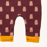 A close up of the Little Green Radicals everyday dungarees in brown bears showing the popper fastener detail around the crotch and yellow trim detail on the leg cuff on dark maroon organic cotton fabric.