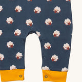 A close up of the Little Green Radicals everyday dungarees in sheep showing the popper fastener detail around the crotch and yellow trim detail on the leg cuff on navy organic cotton fabric.