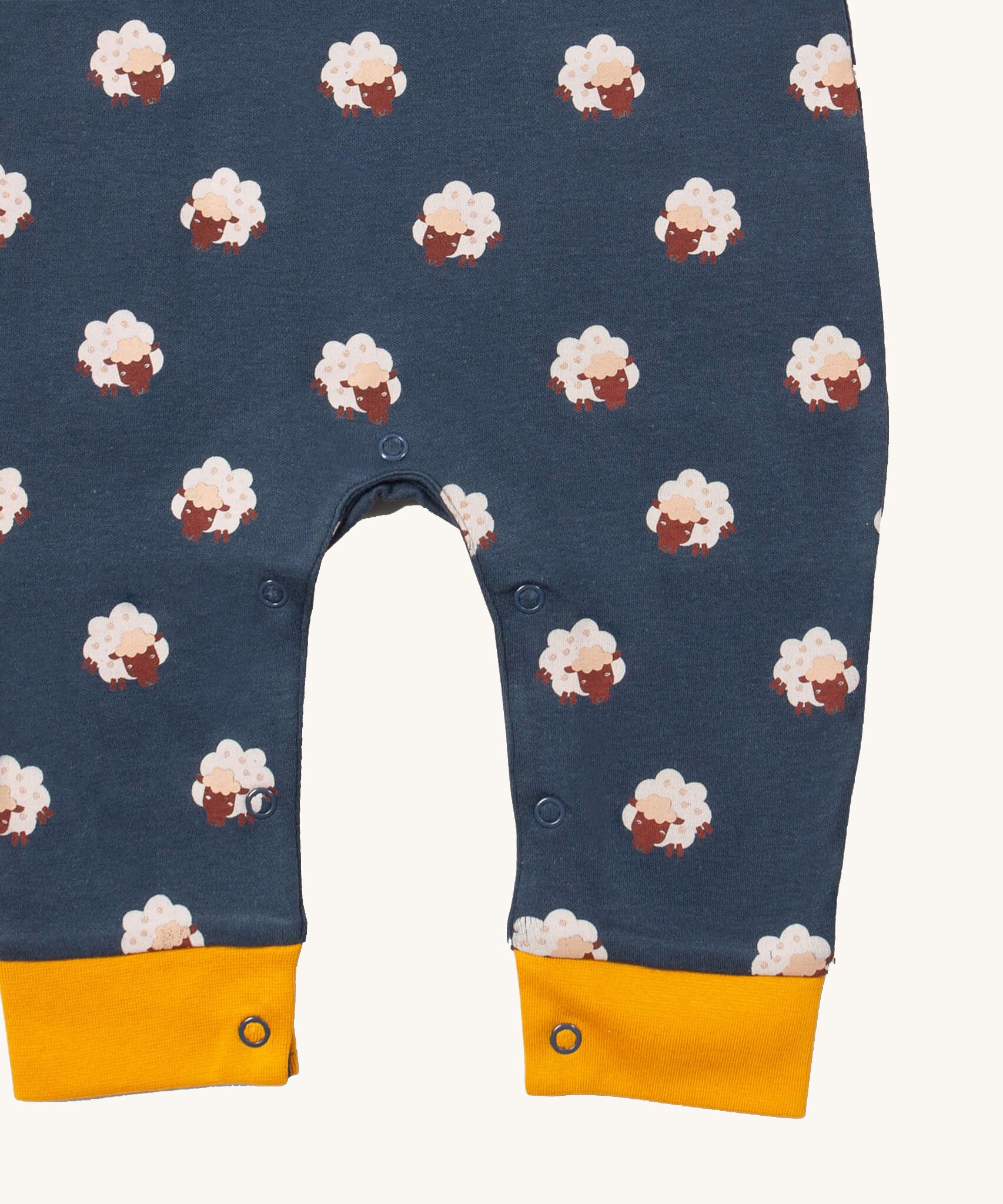A close up of the Little Green Radicals everyday dungarees in sheep showing the popper fastener detail around the crotch and yellow trim detail on the leg cuff on navy organic cotton fabric.