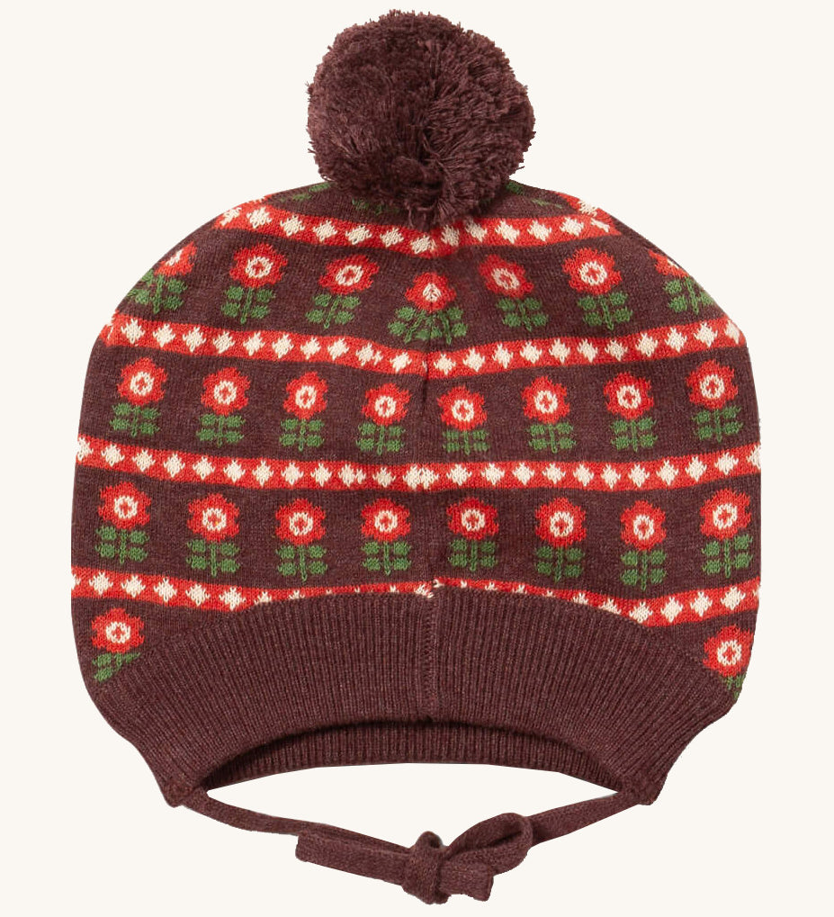 Little Green Radicals flower collecting knitted beanie hat available at Babipur. A dark brown knitted GOTS organic cotton beanie style hat with retro red flowers and matching brown pom pom on top. Features ties for a secure fit.
