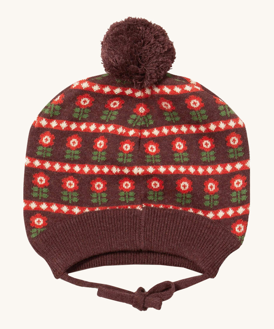 Little Green Radicals flower collecting knitted beanie hat available at Babipur. A dark brown knitted GOTS organic cotton beanie style hat with retro red flowers and matching brown pom pom on top. Features ties for a secure fit.