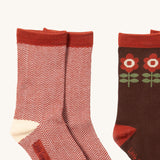 A close up of the red and white striped Little Green Radicals ankle socks next to the brown flower ankle sock showing zig zag stripe and retro flower detail on organic cotton fabric.