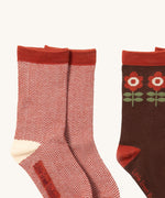 A close up of the red and white striped Little Green Radicals ankle socks next to the brown flower ankle sock showing zig zag stripe and retro flower detail on organic cotton fabric.