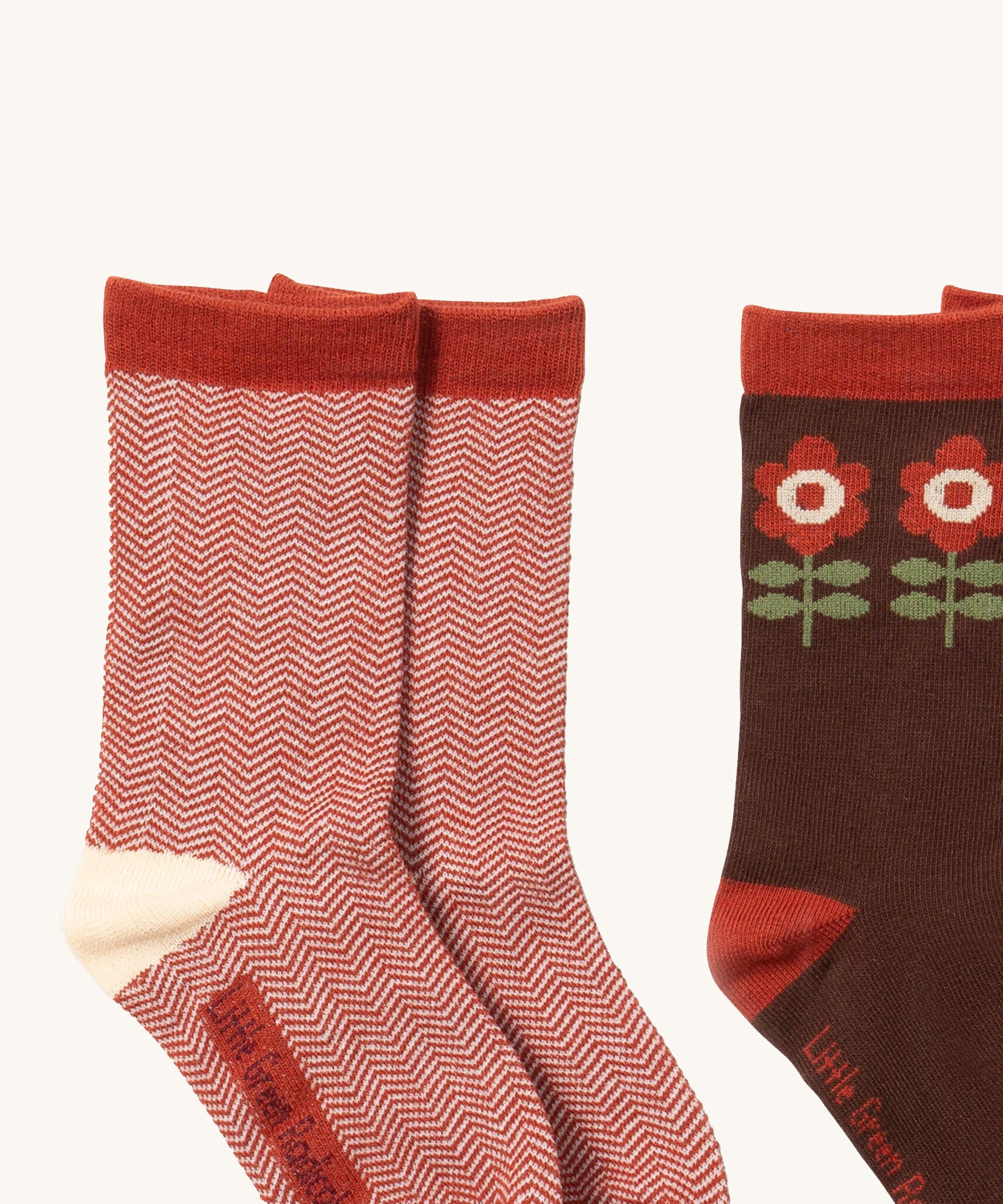 A close up of the red and white striped Little Green Radicals ankle socks next to the brown flower ankle sock showing zig zag stripe and retro flower detail on organic cotton fabric.
