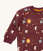 A close up of the Little Green Radicals flying birds quilted sweatshirt that's available at Babipur. Showing the collar and cuff detail dark maroon organic cotton fabric with cute prints of flying birds