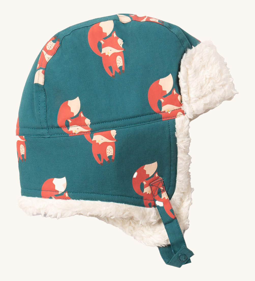 Little Green Radials sherpa fleece cosy hat in foxes. A GOTS organic cotton turquoise hat with turn up ear flaps and a white sherpa style fleece inner. Features a chin strap with popper fastener for a secure fit
