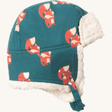 Little Green Radials sherpa fleece cosy hat in foxes. A GOTS organic cotton turquoise hat with turn up ear flaps and a white sherpa style fleece inner. Features a chin strap with popper fastener for a secure fit