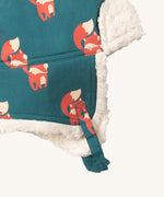 A close up of the Little Green Radials sherpa fleece cosy hat in foxes. Showing the foldable ear flaps, the white sherpa fleece inner and chin strap detail on organic cotton fabric