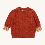 Little Green Radicals ginger aran knitted jumper available at Babipur. A GOTS organic cotton jumper in dark orange with a thick cable knit on the body and a striped design on the cuffs.