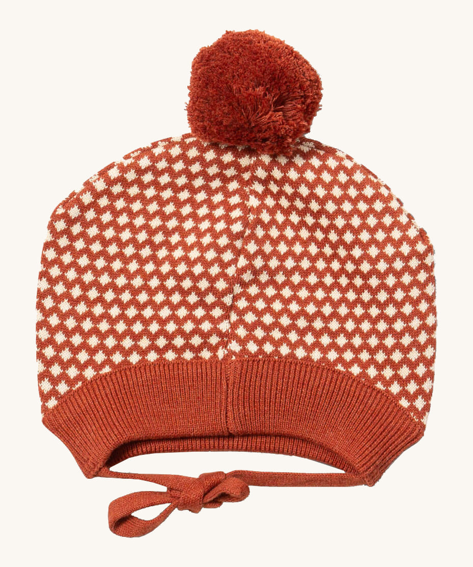 Little Green Radicals ginger diamond knitted beanie hat available at Babipur. A  knitted GOTS organic cotton beanie style hat with a dark orange and cream diamond design and light brown pom pom on top. Features matching dark orange ties for a secure fit.