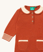 A close up of the Little Green Radicals ginger knitted collar dress. showing the cream collar and button fastener detail on dark orange organic cotton fabric