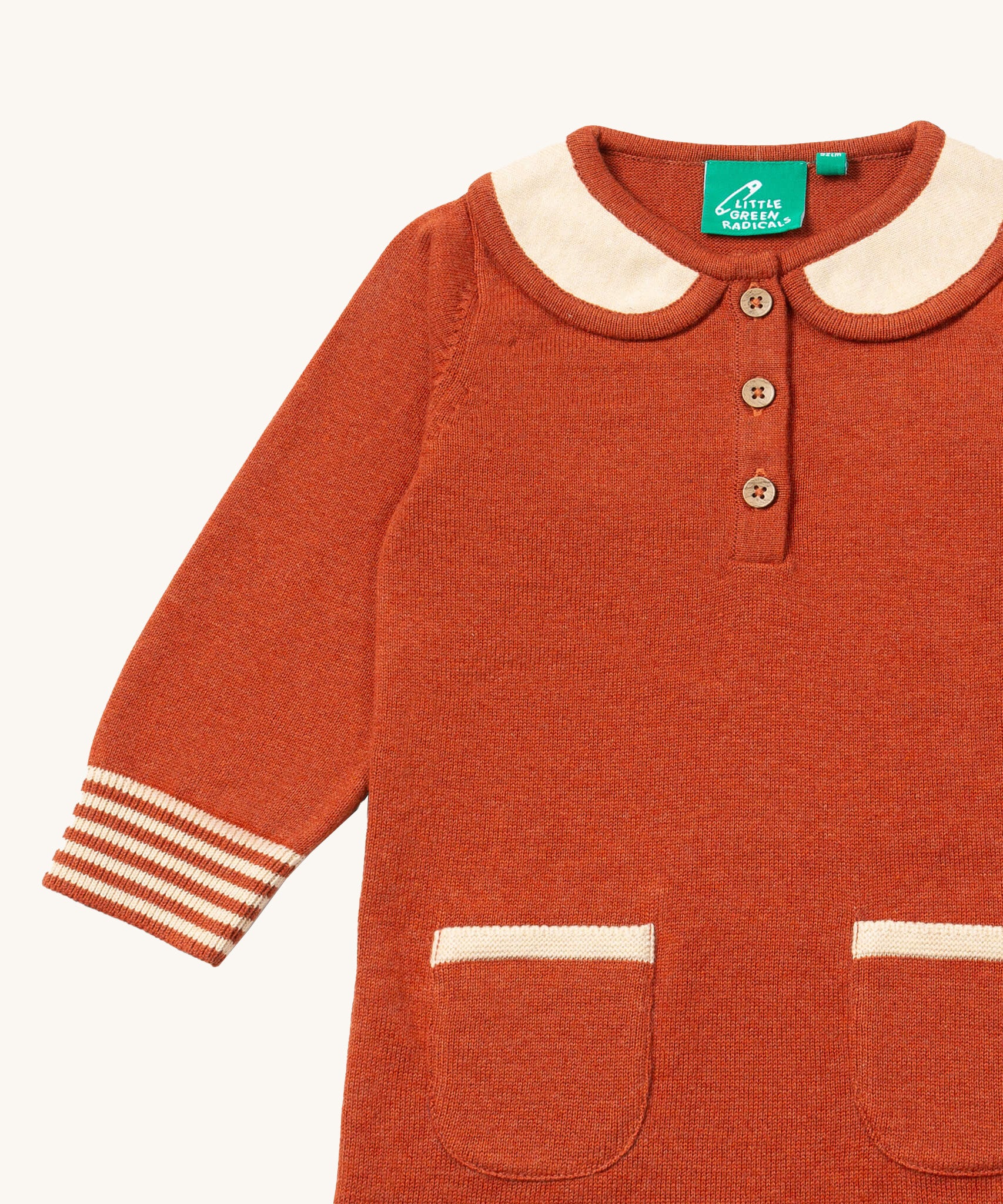 A close up of the Little Green Radicals ginger knitted collar dress. showing the cream collar and button fastener detail on dark orange organic cotton fabric
