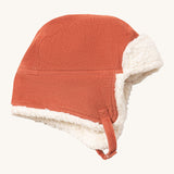 Little Green Radials sherpa fleece cosy hat in ginger available at Babipur. A GOTS organic cotton ginger hat in a corduroy style with turn up ear flaps and a white sherpa style fleece inner. Features a chin strap with popper fastener for a secure fit