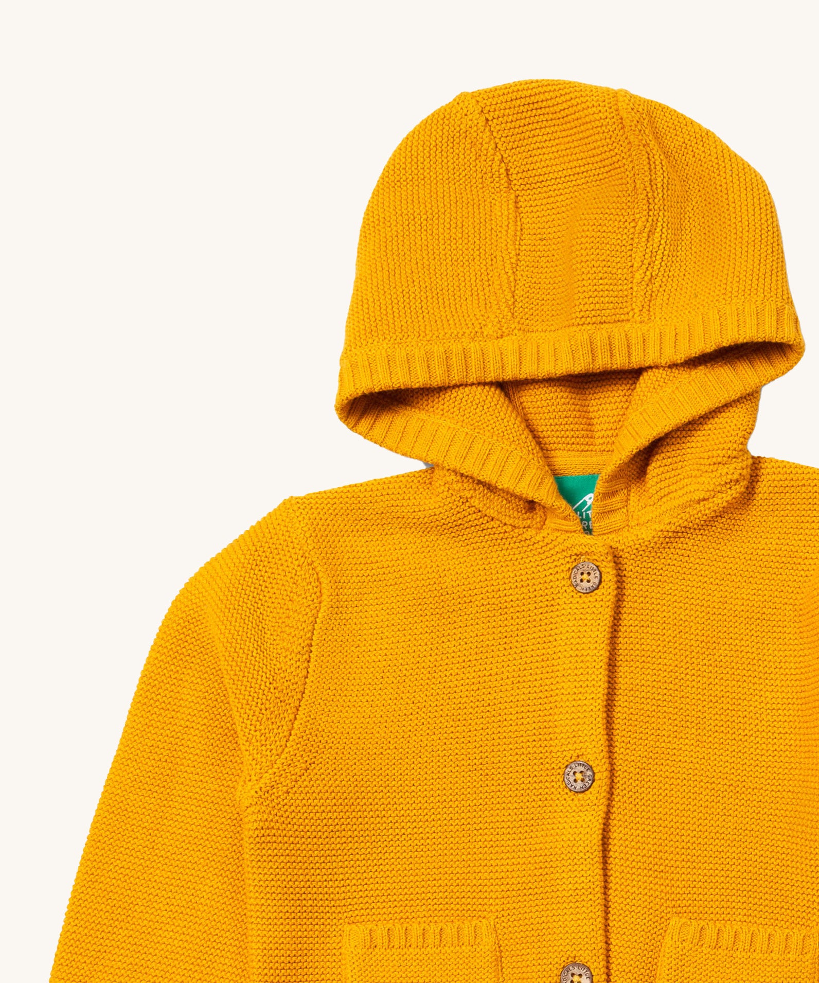 A close up of the Little Green Radicals gold snuggly hooded knitted cardigan. Showing the generous hood detail and button fasteners down the middle yellow organic cotton fabric.