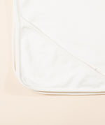 A close up of the Little Green Radicals hooded blanket showing the hood detail on the corner on white organic cotton fabric