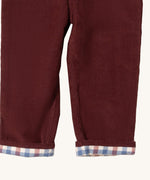 A close up of the Little Green Radicals jeans in chocolate corduroy. Showing the corduroy detail  and check design inner on dark maroon organic cotton fabric