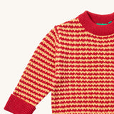 A close up of the Little Green Radicals snuggly knitted jumper in juniper stripe. Showing the yellow and pale red stripe knit detail and the matching pale red collar and turned up cuff