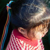 A child wearing the Little Green Radicals snuggly knitted jumper in juniper stripe. Showing a close up of the pale red collar and thick knit detail on striped GOTS organic cotton fabric
