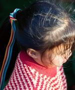 A child wearing the Little Green Radicals snuggly knitted jumper in juniper stripe. Showing a close up of the pale red collar and thick knit detail on striped GOTS organic cotton fabric