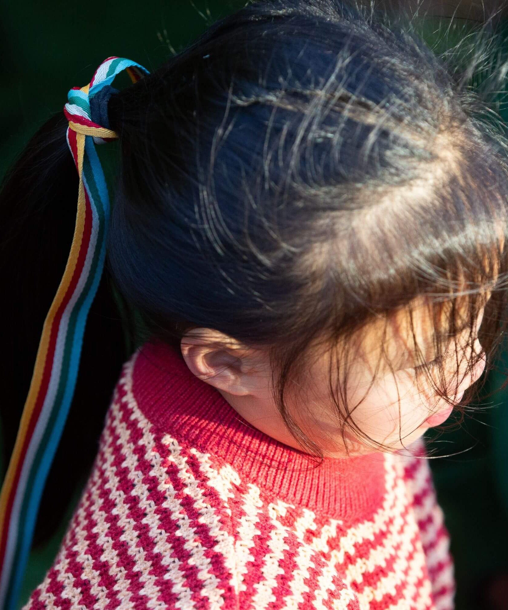 A child wearing the Little Green Radicals snuggly knitted jumper in juniper stripe. Showing a close up of the pale red collar and thick knit detail on striped GOTS organic cotton fabric