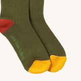 A close up of the green block coloured Little Green Radicals ankle socks showing the yellow and red trim and brand name on the sole on soft organic cotton fabric