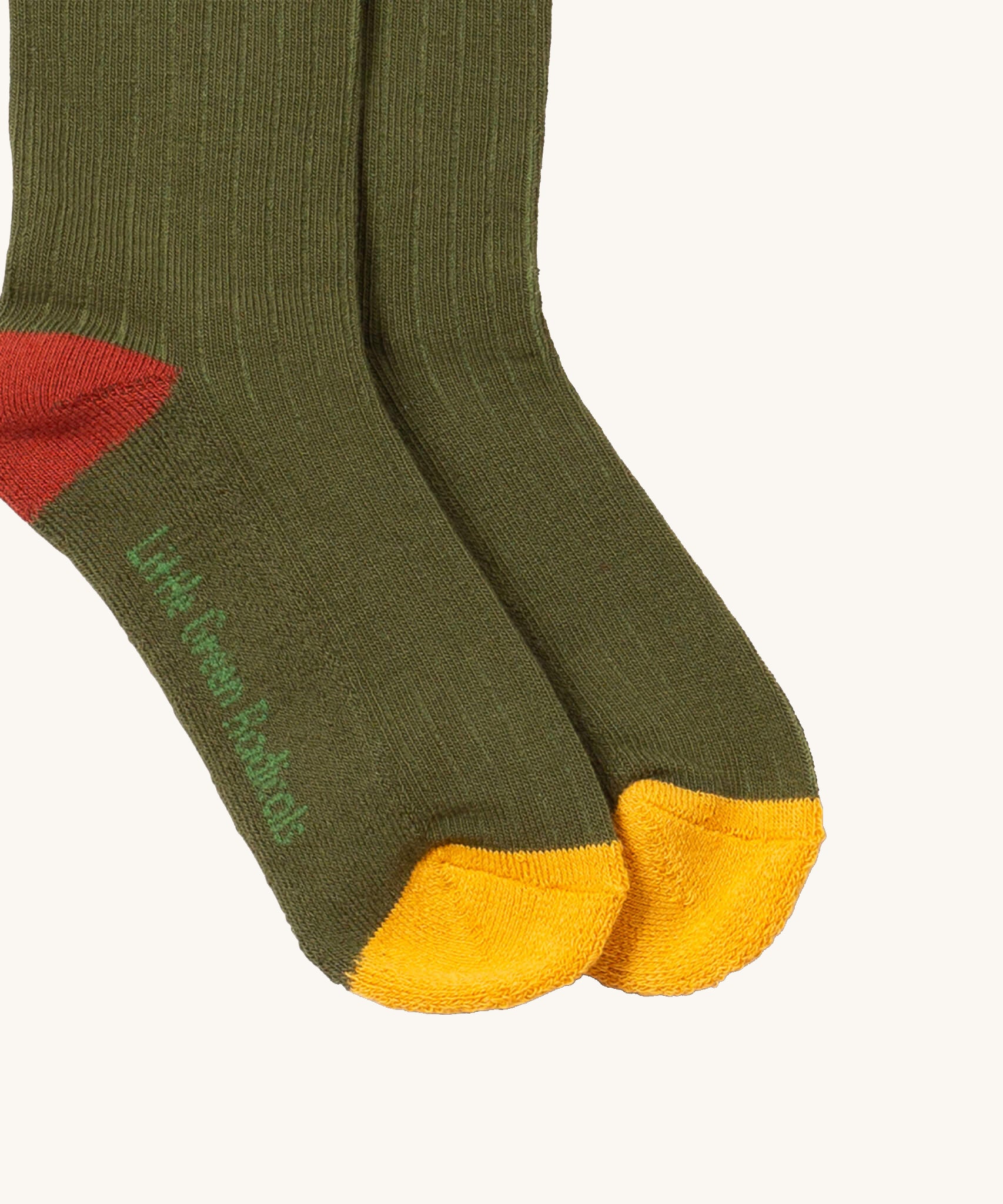 A close up of the green block coloured Little Green Radicals ankle socks showing the yellow and red trim and brand name on the sole on soft organic cotton fabric
